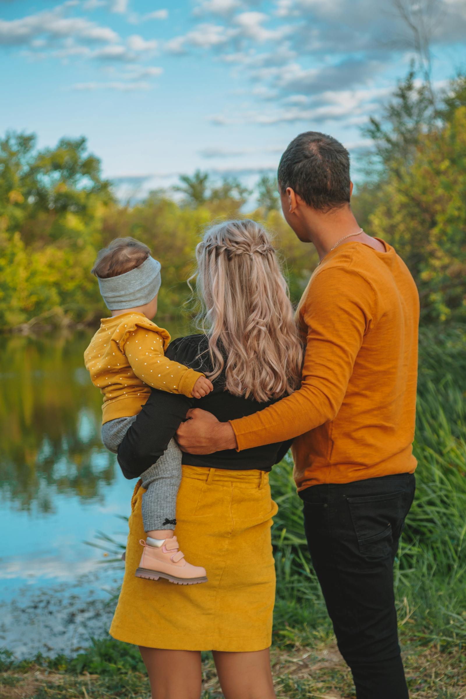 Famille de dos au bord d’une rivière, parents et enfant en automne