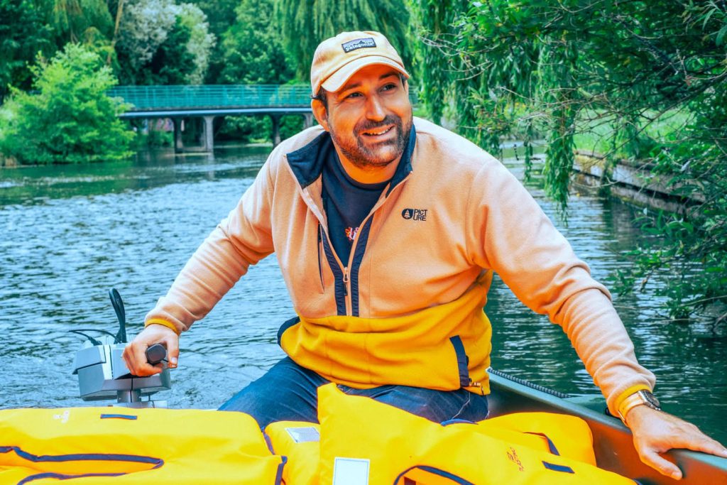 Jules, guide naturaliste, souriant à la barre de sa barque électrique dans les Hortillonnages d’Amiens